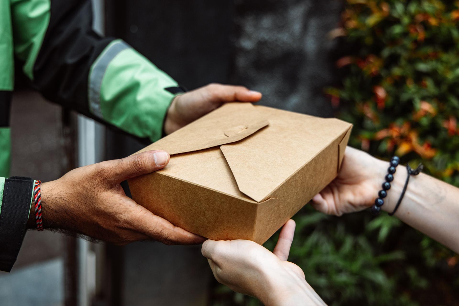 Photo of someone handing a takeout box to someone else